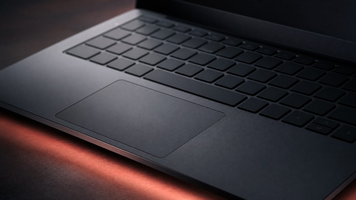 Dark graphite laptop keyboard with a soft coral underglow